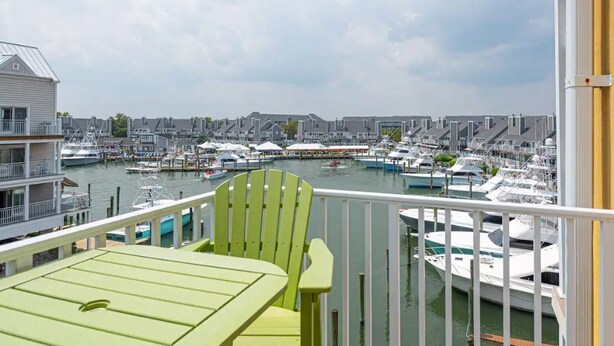 Ein Balkon mit Blick auf einen Hafen voller Boote, ein weißes Gebäude und ein bewölkter Himmel.