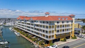 Un hôtel à plusieurs étages doté de balcons, une marina avec des bateaux et un ciel dégagé.