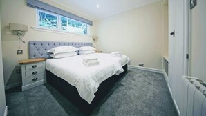 A bedroom with a bed, bedside tables, a window, and a radiator. - Loch Rannoch Highland Club Apartment 9 (Kinloch Rannoch)