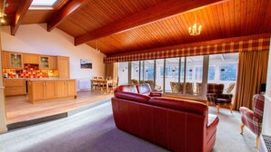 Amplia sala de estar con un sofá rojo, piso de madera y un ventanal con vistas.
