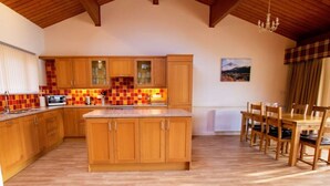 Una cocina amplia con armarios de madera, un salpicadero de azulejos y una zona de comedor con sillas y una mesa de madera.