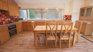 Une cuisine moderne avec des meubles en bois, une table à manger avec des chaises et une grande fenêtre avec des rideaux.