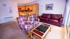 A living room with a red sofa, two plaid armchairs, and a coffee table. - Loch Rannoch Highland Club Studio 3 (Kinloch Rannoch)