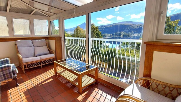 A sunlit balcony with a sofa, two chairs, and a table. - Loch Rannoch Highland Club Studio 8 (Kinloch Rannoch)