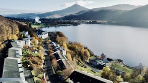 A lakeside hotel with multiple buildings, a view of a mountain, and a body of water. - Loch Rannoch Highland Club Studio 8 (Kinloch Rannoch)