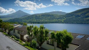 A lakeside view with a mountain in the background, a row of houses with sloped roofs, and a clear sky. - Loch Rannoch Highland Club Studio 8 (Kinloch Rannoch)