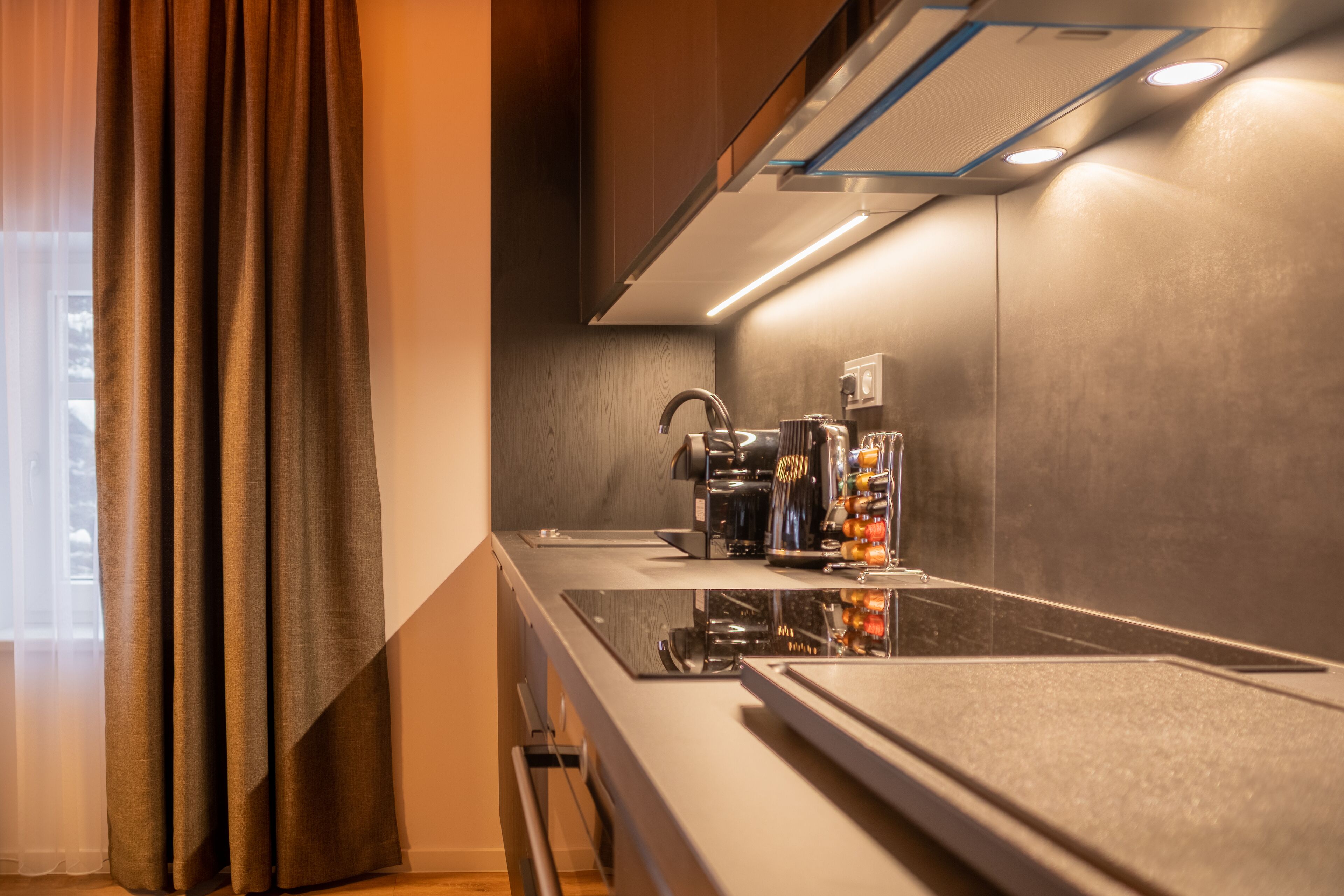A modern kitchen with a built-in stove, a coffee machine, and a wine cooler.