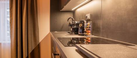 A modern kitchen with a built-in stove, a coffee machine, and a wine cooler.