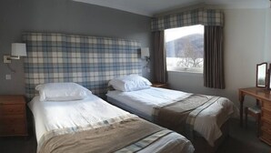 A hotel room with two single beds, a wooden dresser, a nightstand, a lamp, and a window with curtains. - Loch Rannoch Highland Club, Grouse Lodge (Kinloch Rannoch)