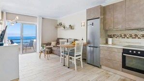Una cocina moderna con un refrigerador grande, horno y un comedor con mesa y sillas.