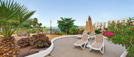 A rooftop lounge area with lounge chairs and a curved pathway.