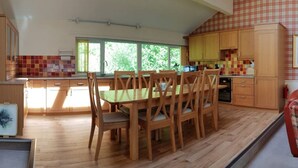 A spacious kitchen with wooden cabinets, a dining table with chairs, and large windows providing natural light. - Loch Rannoch Highland Club, Highland  Lodge 45 (Kinloch Rannoch)