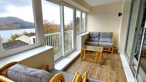 Ein Balkon mit einer Couch, einem kleinen Tisch und einem Stuhl.