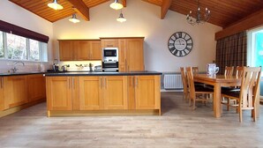 A spacious kitchen with wooden cabinets, a central island, and a dining area with a table and chairs.