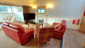 A living room with a sofa, armchair, and a flat-screen TV.