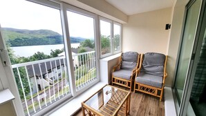 A balcony with wicker furniture and a view of a lake and hills. - Loch Rannoch Highland Club,  Red Deer 5 (Kinloch Rannoch)