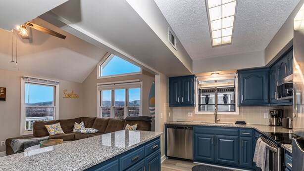 A modern kitchen with blue cabinets, stainless steel appliances, and a large island. - Sleep 8 in this guest fave! All new, fresh & fun!walk to lake and marina. (Holiday Island)