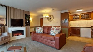 A living room with a fireplace, a sofa, a chair, and a small table. - Loch Rannoch Highland Club, Otter Lodge 3 (Kinloch Rannoch)