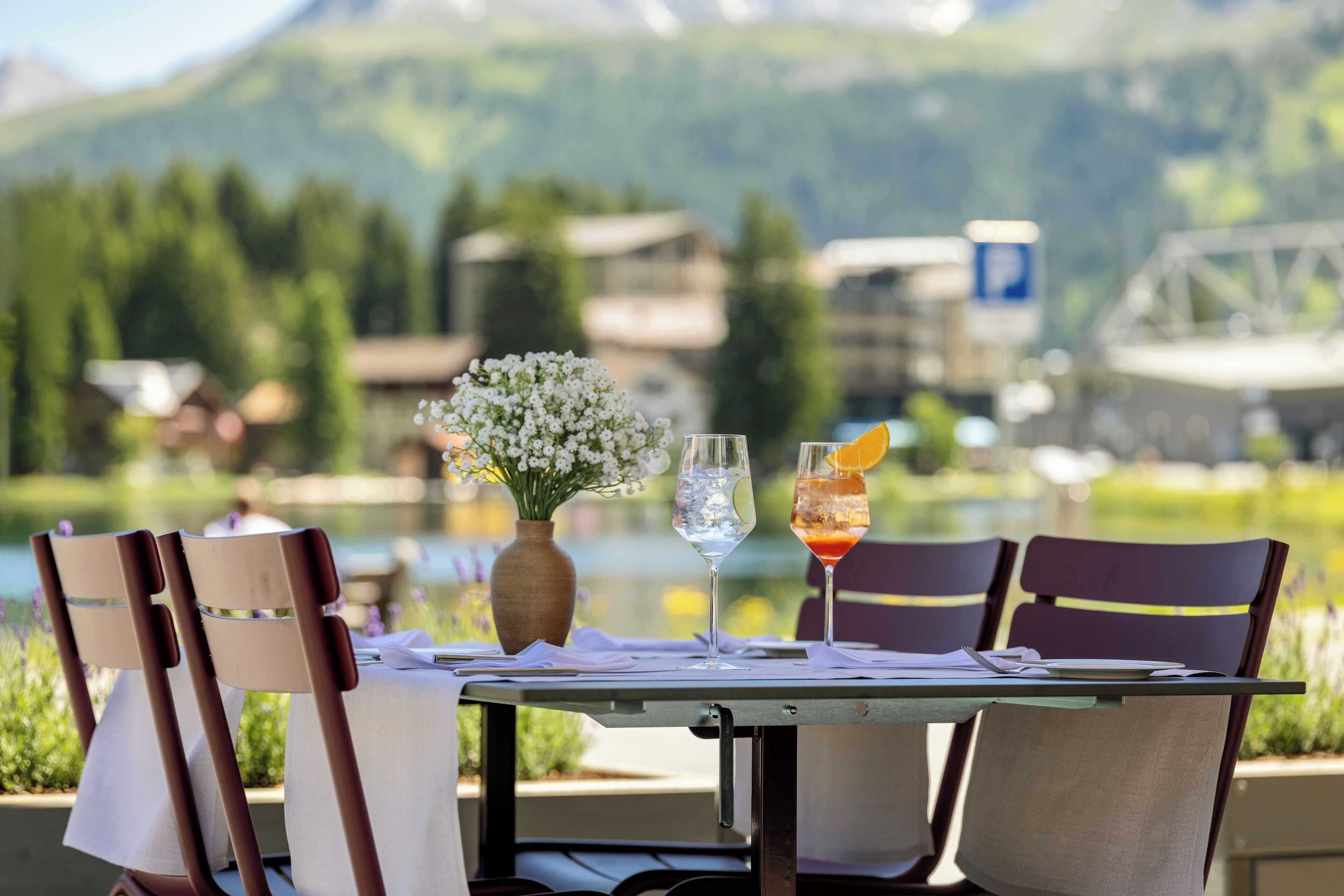 A table set for two with a view of a lake and mountains in the background.