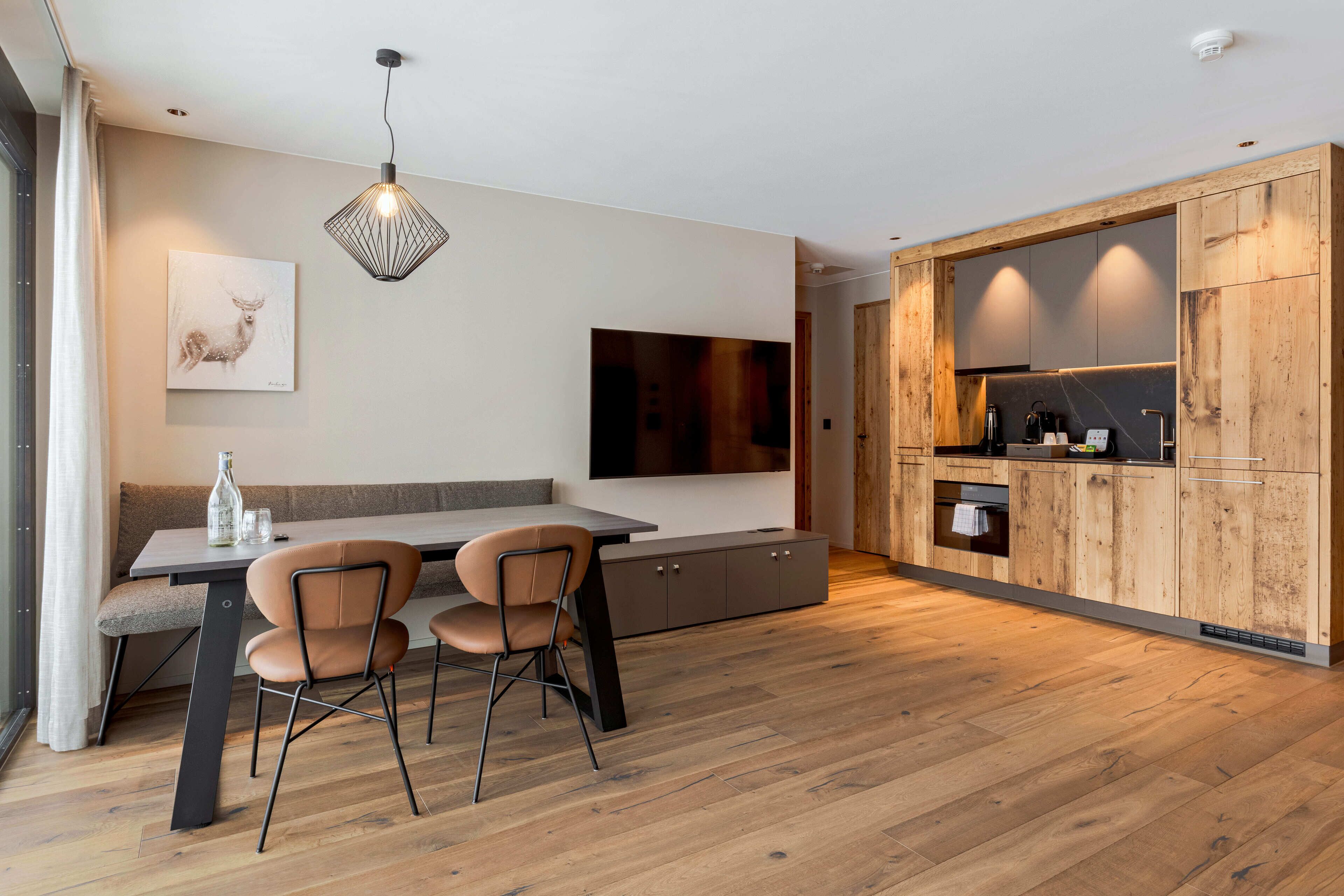 Eine moderne Küche mit Holzausstattung, integriertem Backofen und einem Essbereich mit Tisch und Stühlen.