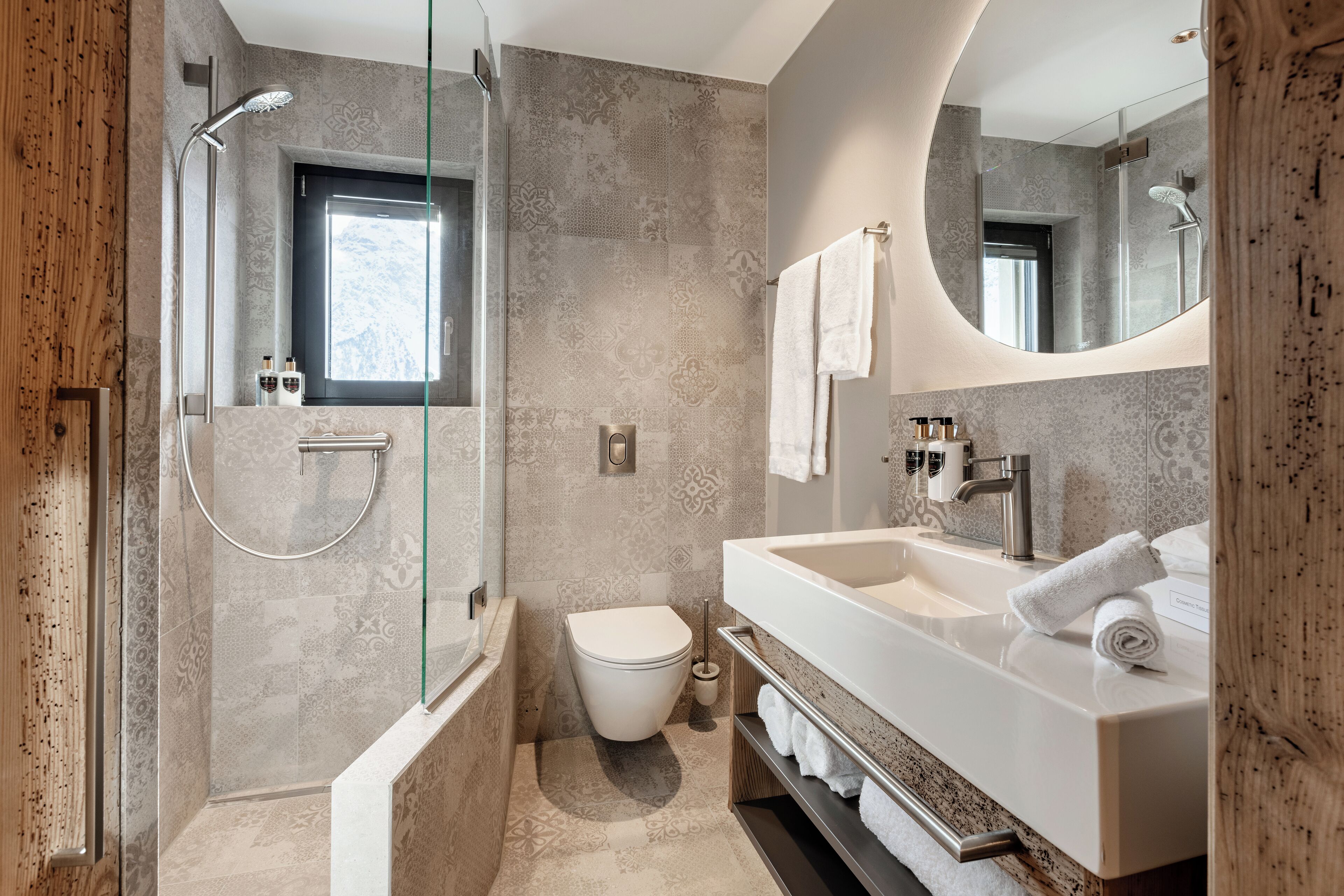 Een moderne badkamer met een douchecabine van glas, een toilet en een wastafel met spiegel.