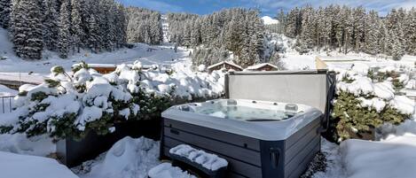 A hot tub in a snowy outdoor setting with a mountainous backdrop.