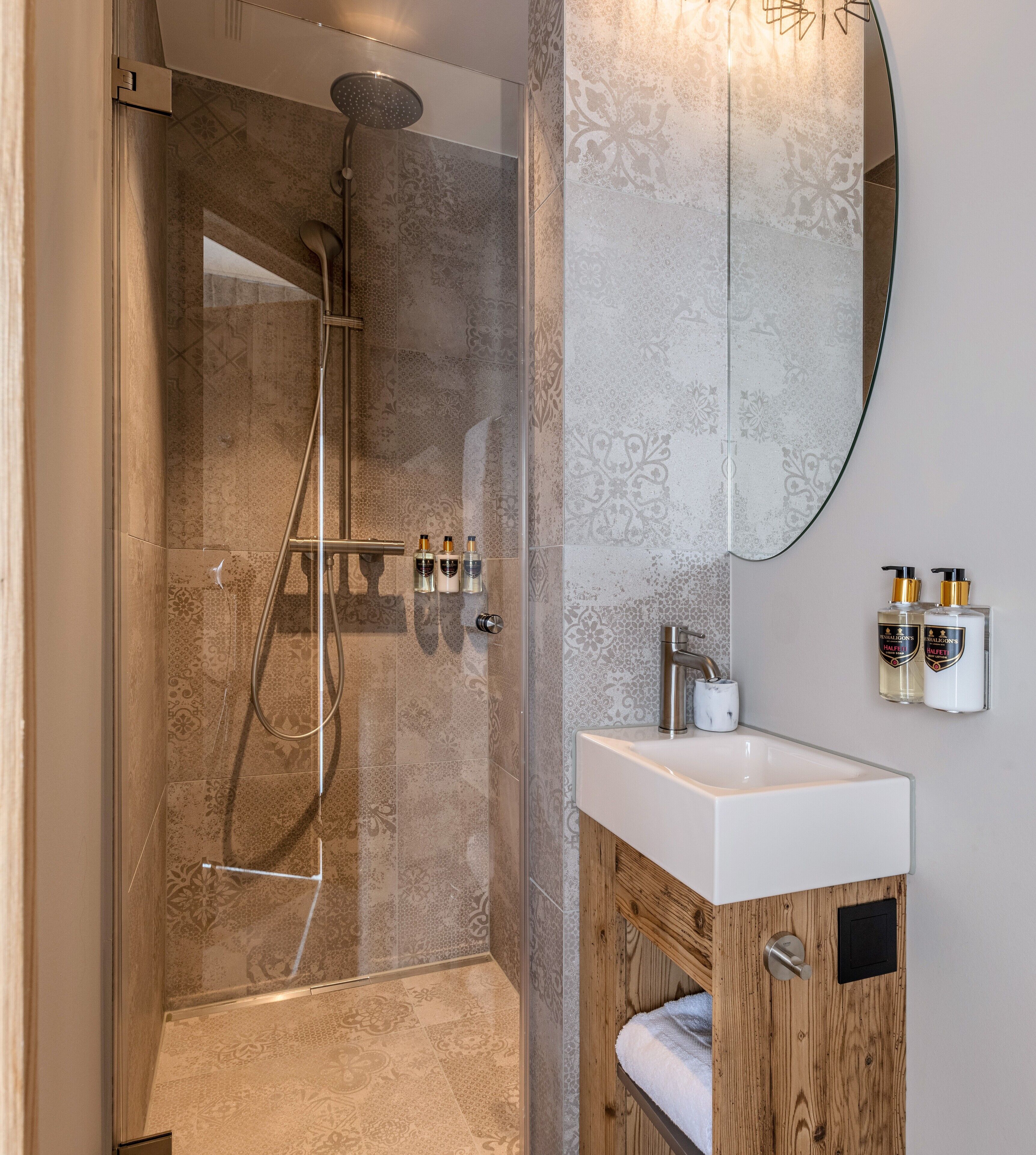A modern bathroom with a glass-enclosed shower, a wooden vanity with a white sink, and a large mirror.