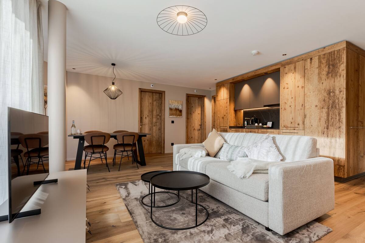 A modern living room with a sofa, coffee table, and dining area.