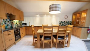 A modern kitchen with wooden cabinets, a central island, and a dining table with chairs.