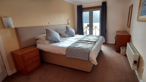A bedroom with a bed, bedside tables, a radiator, and a window with curtains. - Loch Rannoch Highland Club, Highland Lodge 8 (Kinloch Rannoch)