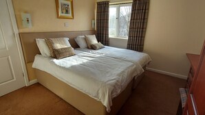 A bedroom with a bed, a window with curtains, and a door. - Loch Rannoch Highland Club, Highland Lodge 46 (Kinloch Rannoch)