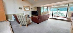 A living room with a fireplace, a television, and a large sliding glass door leading to a balcony.