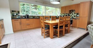 Enjoy meals in this kitchen with a central island and dining table for four, offering a view of the surrounding greenery.