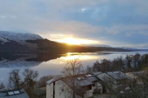A lakeside view with a building in the foreground, surrounded by trees and mountains in the background. - Loch Rannoch Highland Club, Otter Lodge 6 (Kinloch Rannoch)