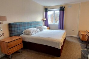 A bedroom with a bed, a nightstand, a wooden dresser, and a window with curtains. - Loch Rannoch Highland Club, Highland Lodge 44 (Kinloch Rannoch)