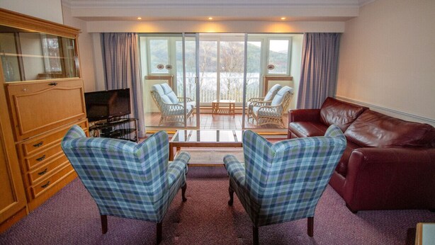 A living room with a television, two plaid armchairs, a red sofa, and a wooden cabinet. - Loch Rannoch Highland Club, Studio 5 (Kinloch Rannoch)