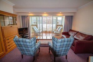 A living room with a television, two plaid armchairs, a red sofa, and a wooden cabinet. - Loch Rannoch Highland Club, Studio 5 (Kinloch Rannoch)