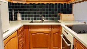 A compact kitchen with wooden cabinets, a tiled backsplash, and a built-in oven. - Loch Rannoch Highland Club, Studio 5 (Kinloch Rannoch)