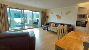 A spacious living room with a sofa, a dining table, and a kitchen area with modern appliances. - Loch Rannoch Highland Club, Pine Martin Lodge 2 (Kinloch Rannoch)