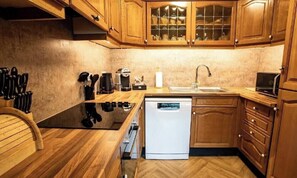 Una cocina con armarios de madera, lavavajillas, cafetera y microondas.