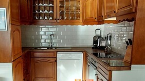 Una cocina compacta con armarios de madera, lavavajillas integrado y salpicadero de azulejos.