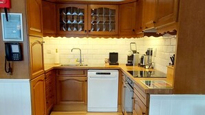 Een moderne keuken met houten kastjes, een inbouwvaatwasser en een betegelde achterwand.