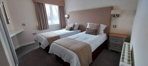 A room with two beds, a nightstand, a lamp, and a window with curtains. - Loch Rannoch Highland Lodge 41 (Kinloch Rannoch)