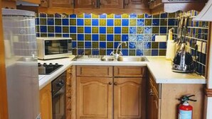 A kitchen with wooden cabinets, a tiled backsplash, a stainless steel refrigerator, and a fire extinguisher. - Loch Rannoch Highland Lodges Apartment 13 (Kinloch Rannoch)