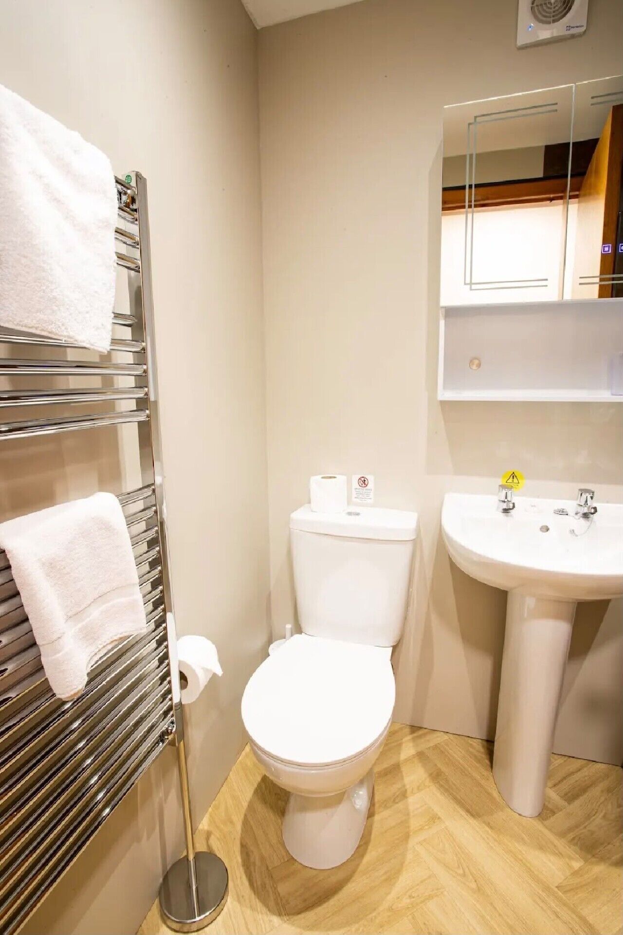 A bathroom with a toilet, a sink, a towel rack, and a mirror.