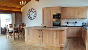Eine moderne Küche mit Holzausstattung, einer zentralen Kochinsel und einem eingebauten Backofen.