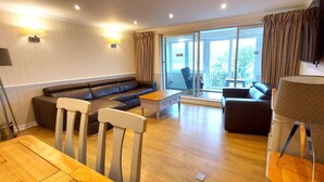 A modern living room with a sofa, chairs, a coffee table, and a TV.