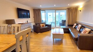 Un salón espacioso con una mesa de comedor de madera, dos sofás, una mesa de centro y un televisor en la pared.