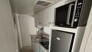 A compact kitchen with a microwave, refrigerator, and stove. - Mobile home with air conditioning near the ocean and plenty of places to explore (La Tremblade)