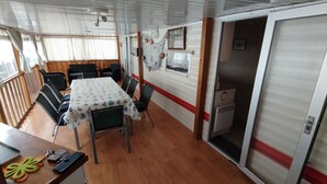 A dining area with a table and chairs, a window with curtains, and a door leading to another room. - Mobile home with air conditioning near the ocean and plenty of places to explore (La Tremblade)